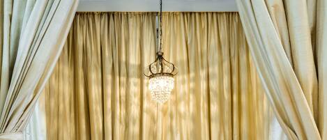 A room with a bed, a desk, and a hanging light fixture.