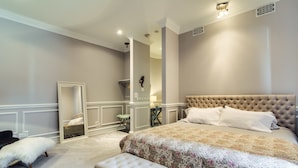 A bedroom with a large bed, a bench, a chair, and a mirror. - The Golden Arm (Chicago)