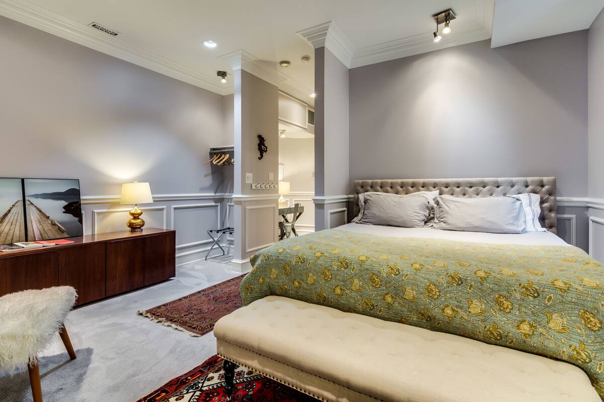 A bedroom with a large bed, a bench, a desk, and a chair.