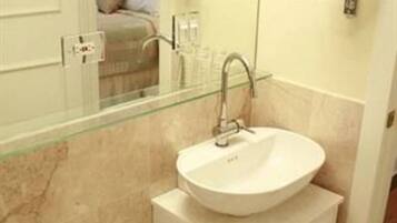 Un bagno con un lavandino bianco, cabina doccia in vetro, un water e uno specchio.
