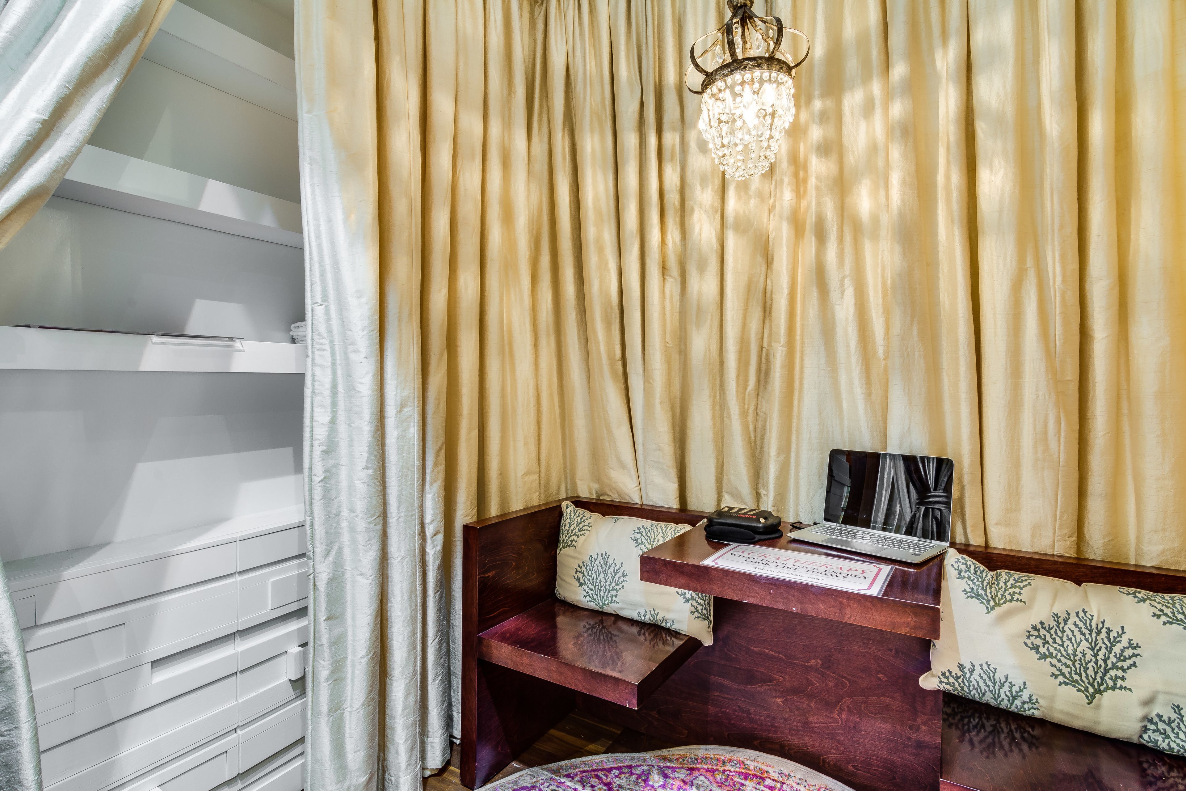 Ein Zimmer mit einer hölzernen Bank, einem Laptop und einer Chandelier.