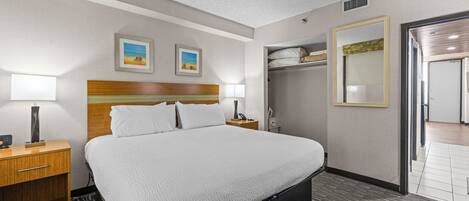 A hotel room with a bed, bedside tables, a wardrobe, and a mirror.