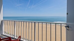 Een balkon met uitzicht op strand en zee.
