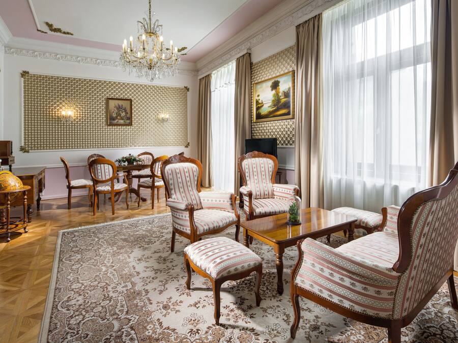 Comedor formal con candelabro, papel tapiz estampado y un ventanal con cortinas.