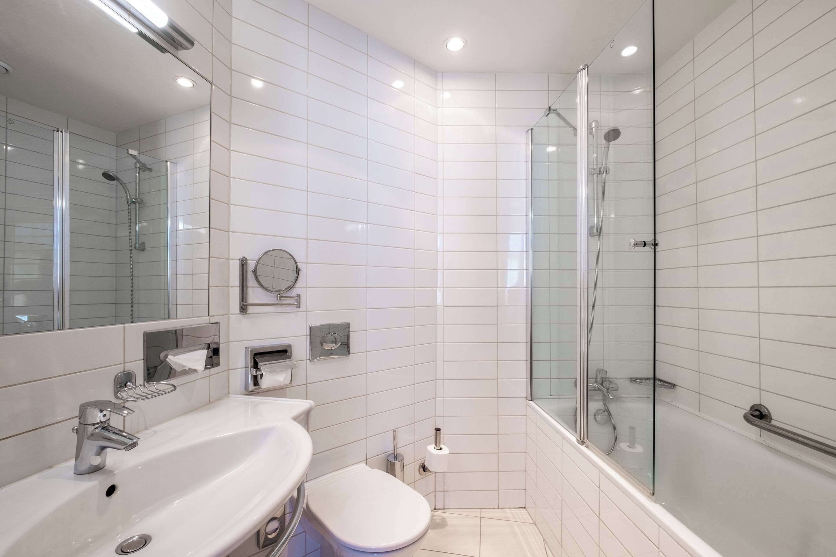 Ein modernes Badezimmer mit einer Duschkabine, einem weißen Waschbecken und einer Toilette.