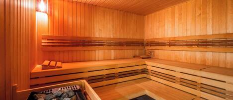 A sauna with wooden benches and a stone heating element.