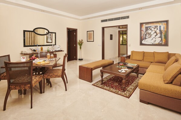 Un salón amplio con un sofá grande, un comedor con una mesa y sillas de madera, y un pasillo que conduce a otra habitación.