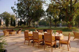 Un espacio de comedor al aire libre con mobiliario de mimbre y una mesa dispuesta para seis personas.
