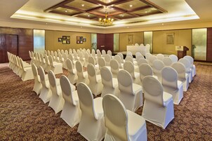 A conference room with rows of white chairs, a podium, and a carpeted floor.
