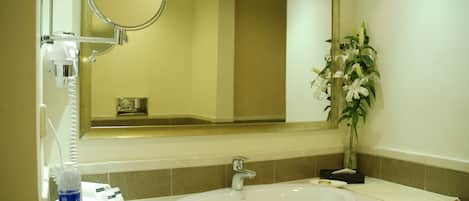 A hotel bathroom with a sink, mirror, and toiletries.