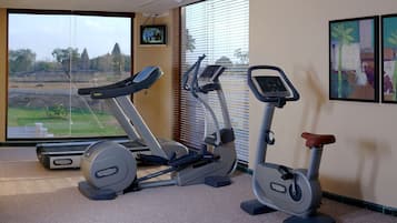 A home gym with a treadmill, elliptical, and stationary bike.
