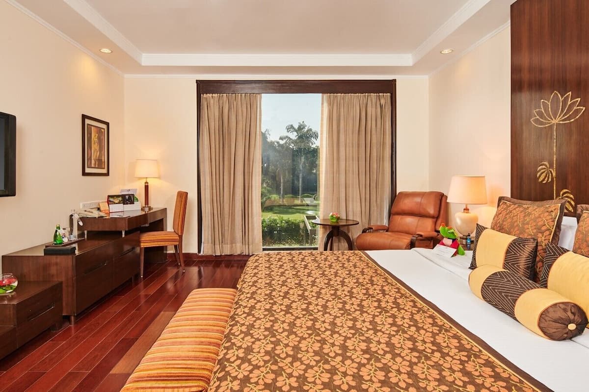 A hotel room with a large bed, a desk, a chair, and a TV.