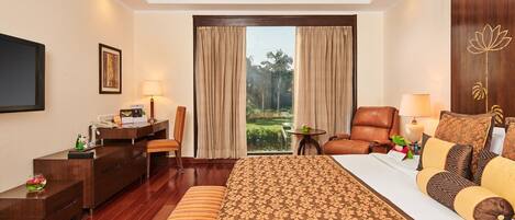 A hotel room with a large bed, a desk, a chair, and a TV.