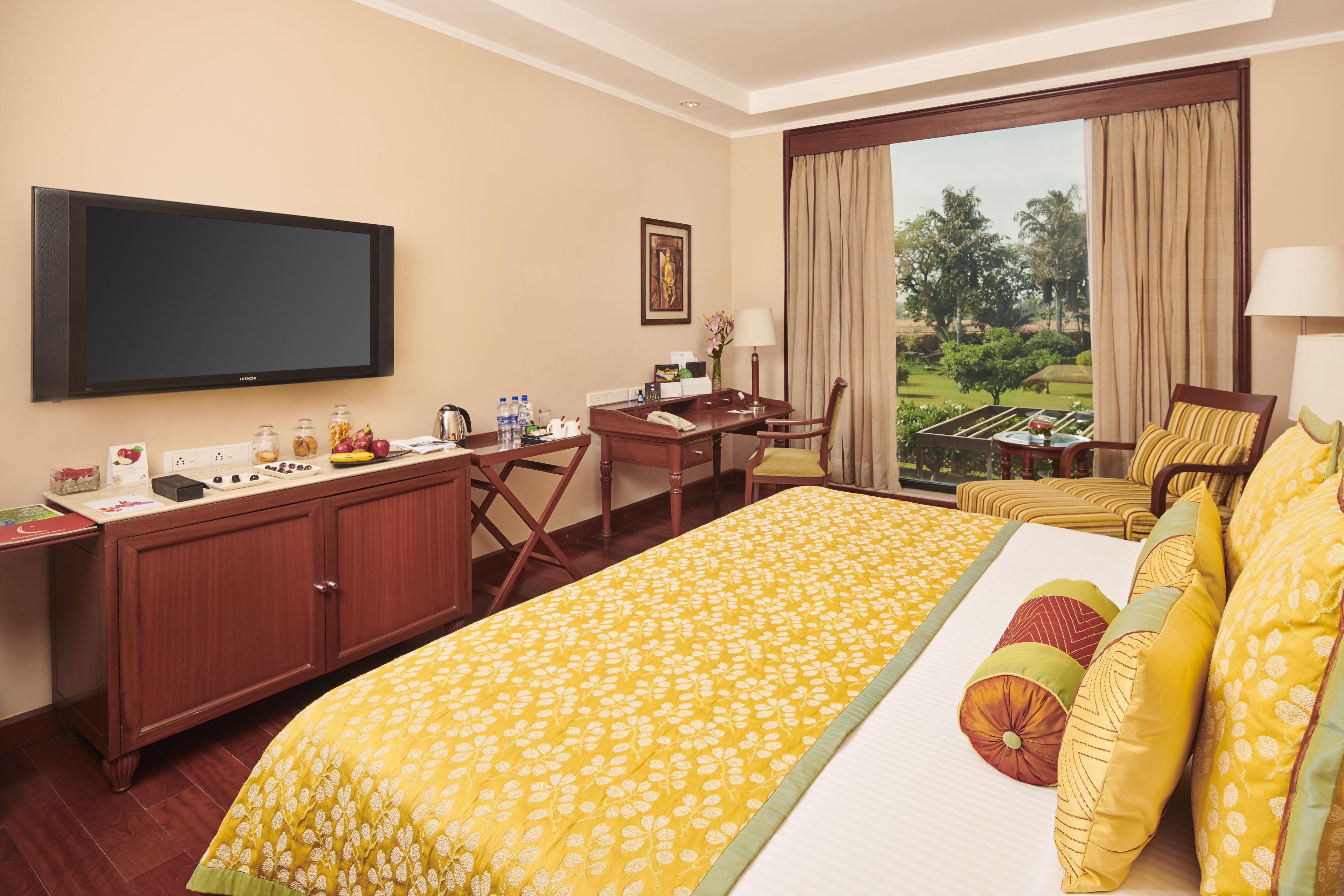 A hotel room with a large bed, a desk, a television, and a view of the outdoors.