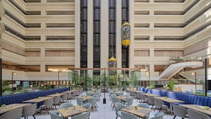 Een meerlaags atrium met zitgedeeltes, een centrale trap en een glazen lift.