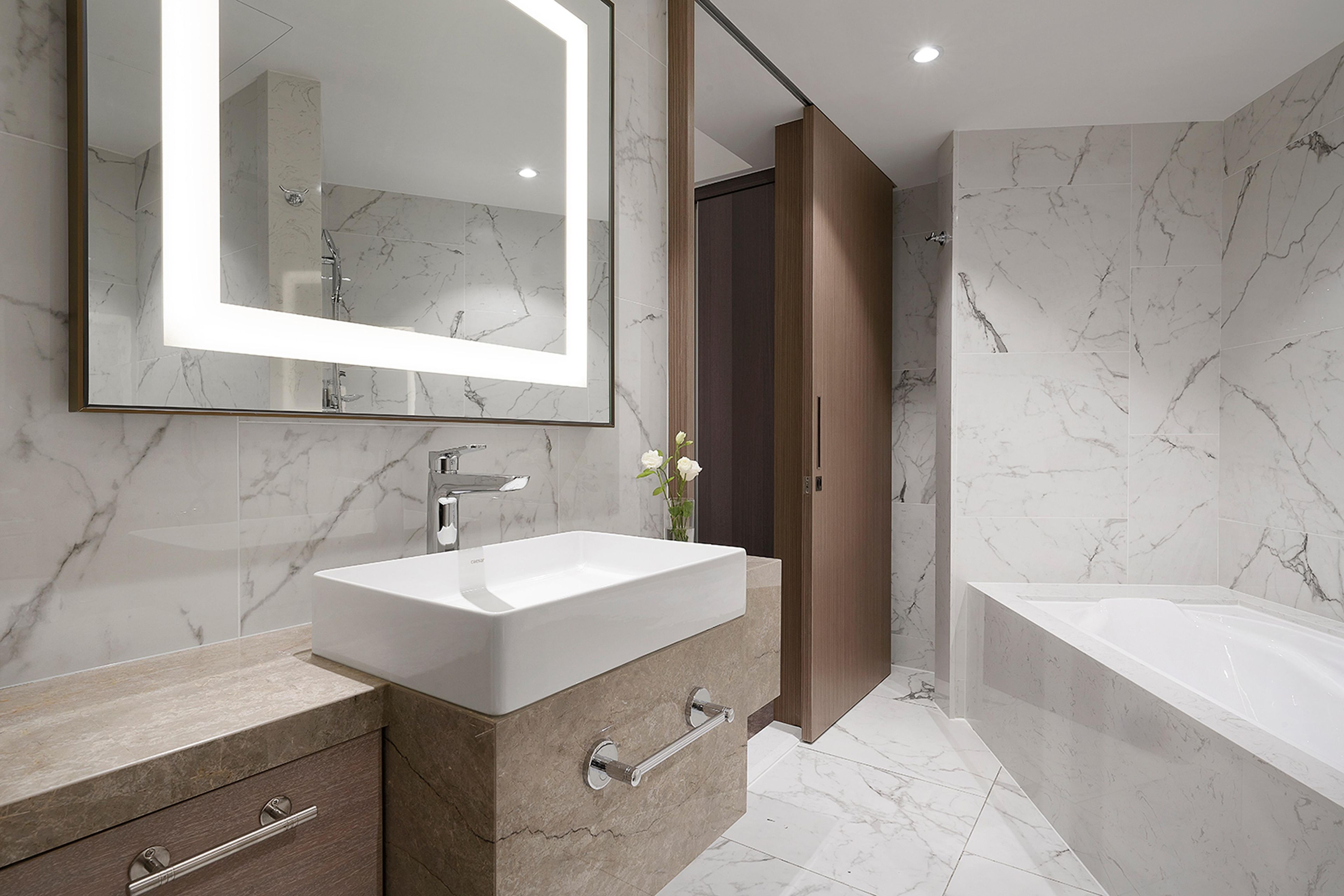 A modern bathroom with a large mirror, a sink, a bathtub, and a shower area.