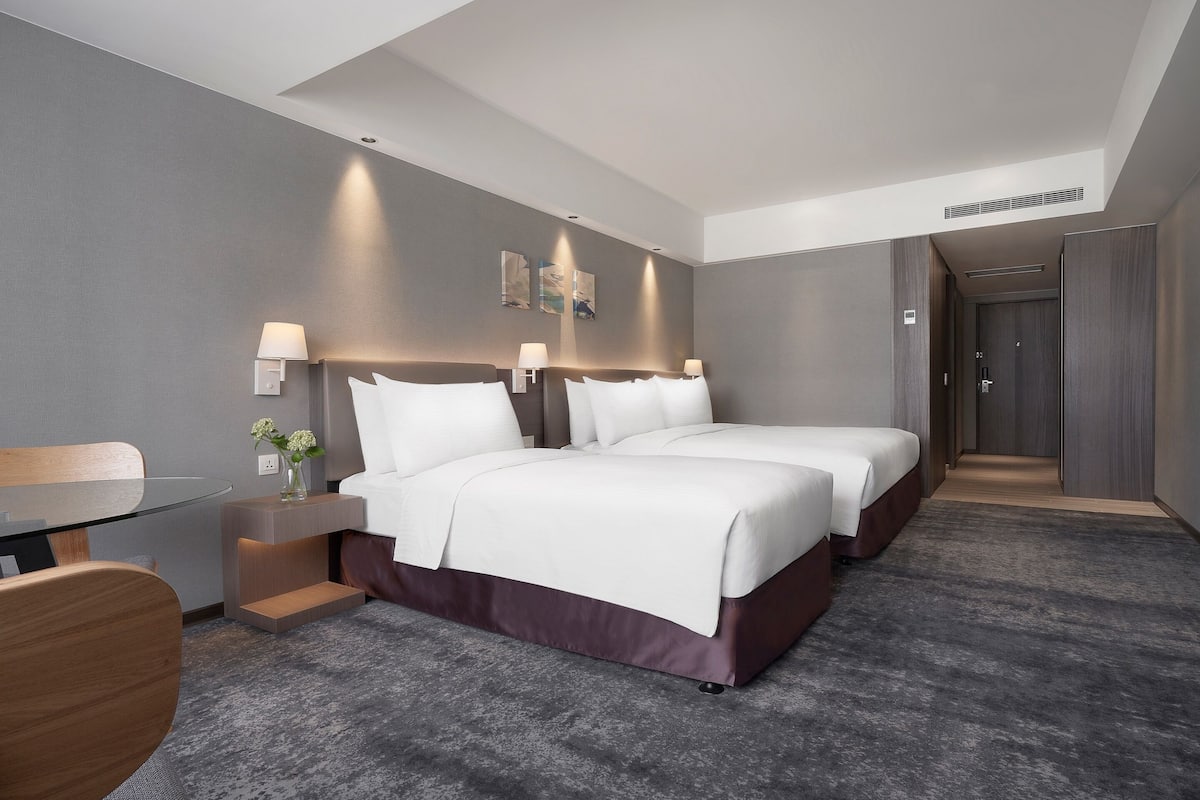 A hotel room with two beds, a desk, and a chair.