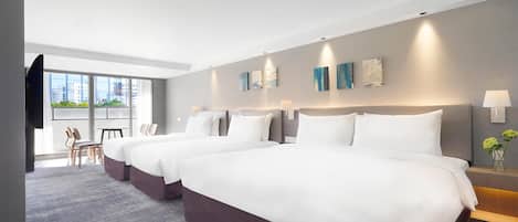 Een hotelkamer met twee bedden, een bureau, stoelen, een raam met uitzicht en kunst aan de muur.