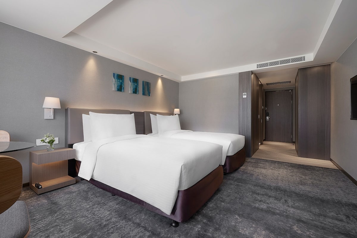A modern hotel room with a large bed, bedside tables, a desk, and a walk-in closet.