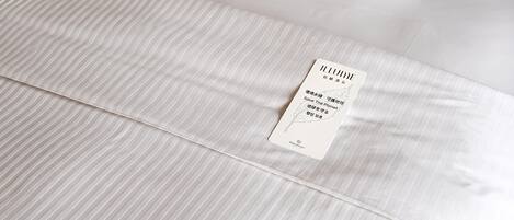 A neatly made bed with white linens and a placard on the mattress.