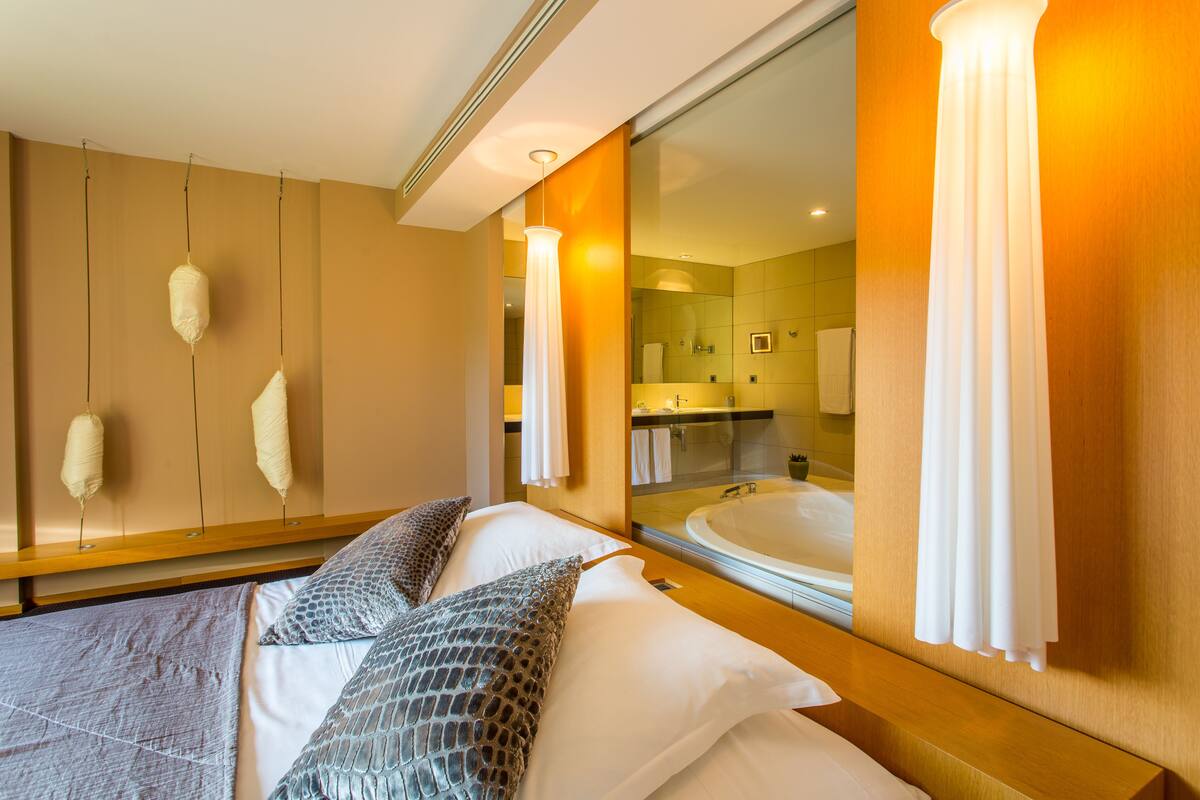 Una camera d'albergo con un letto grande, uno specchio che riflette il bagno e vista sul bagno.