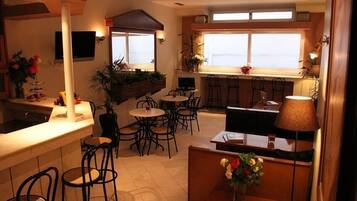 A restaurant with a bar area, multiple seating options including round tables and booths, and large windows providing views.