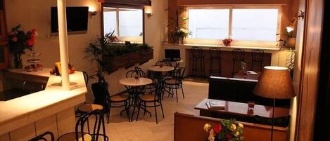 Un restaurant doté d’un bar, de plusieurs types de tables et de banquettes, ainsi que de grandes fenêtres offrant une vue panoramique.