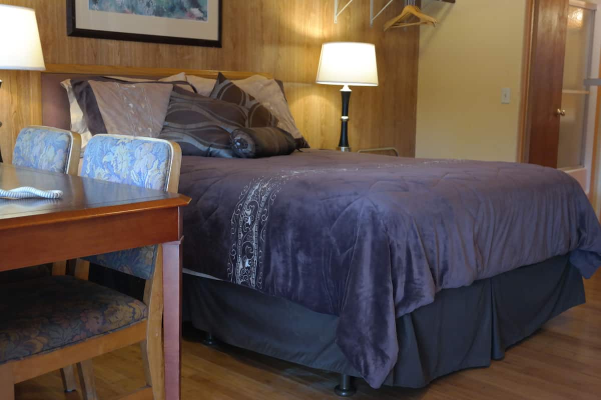 Une chambre à coucher avec un lit, deux chaises, une table et deux lampes.