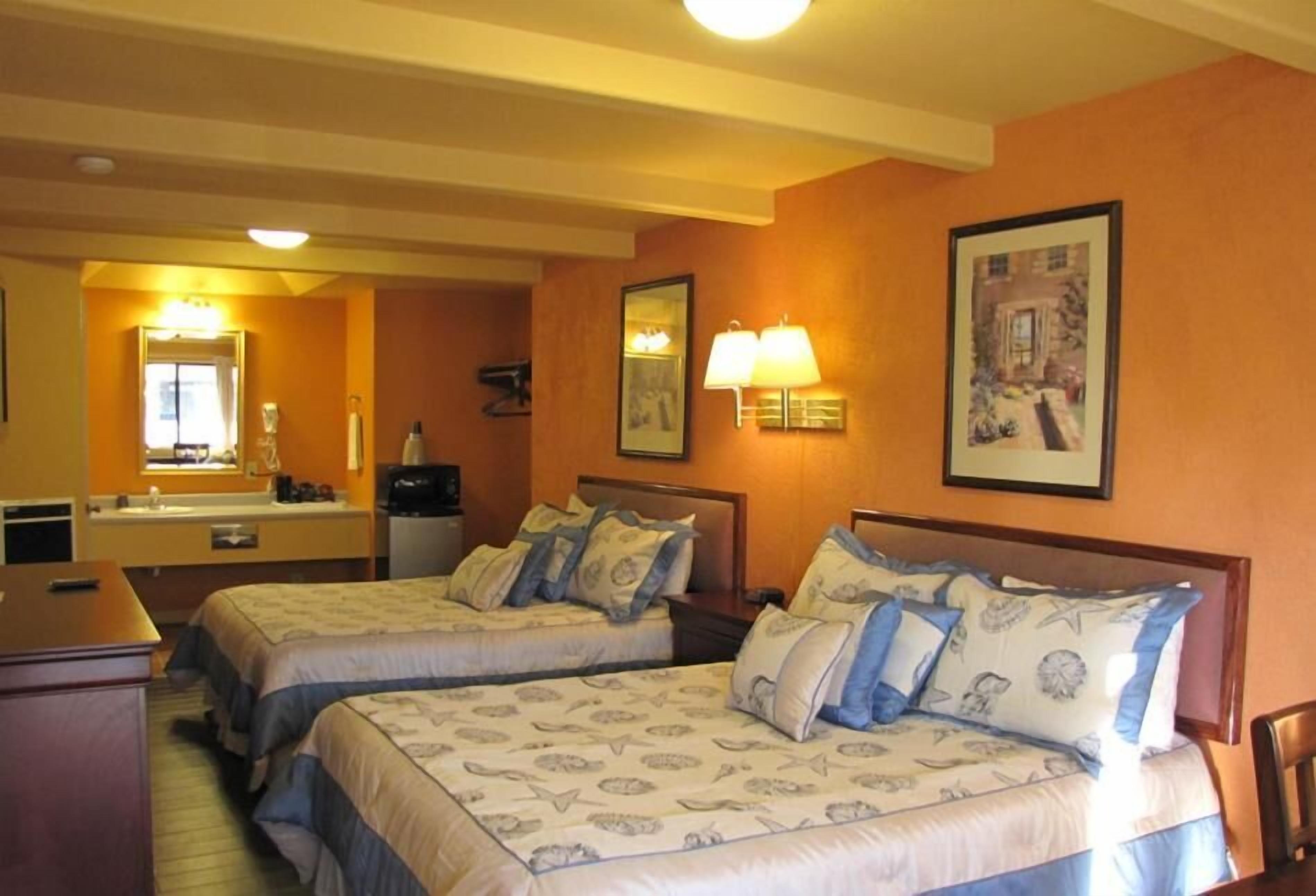 Habitación de hotel con dos camas, un escritorio, un espejo y un baño.