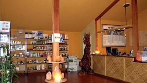 A reception area with a wooden reception desk, a large plant, and shelves stocked with various items. - Coast Inn and Spa Fort Bragg (Fort Bragg)