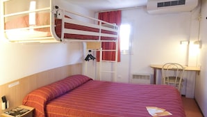 Una cama litera con colcha roja, un escritorio con silla, un perchero y un aire acondicionado instalado en la pared.