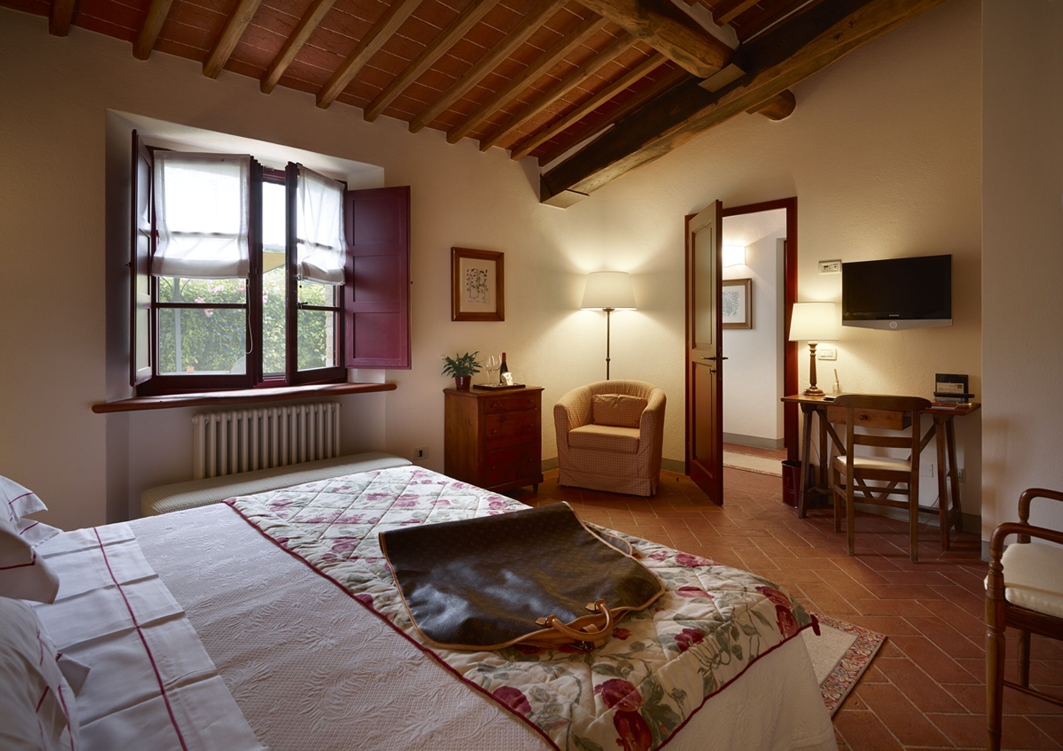 Una camera da letto con un letto, una sedia, una scrivania, una lampada e un televisore.