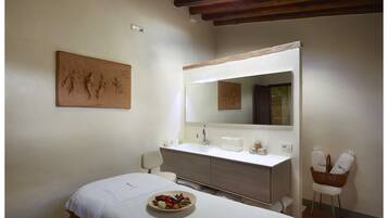Relax in a serene space with a large mirror, a comfortable bed, and a wicker chair.