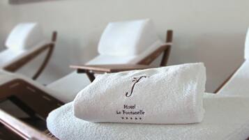 Une serviette blanche, soigneusement pliée et ornée d’un motif brodé, est posée sur une chaise en bois.