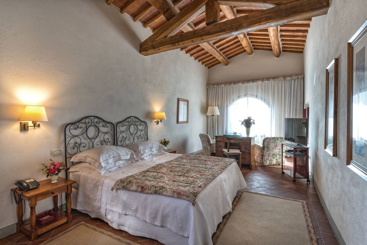 Un dormitorio con cama, lámparas de noche, escritorio y una silla.