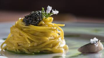 Un plato de pasta amarilla con caviar y una pequeña decoración floral.