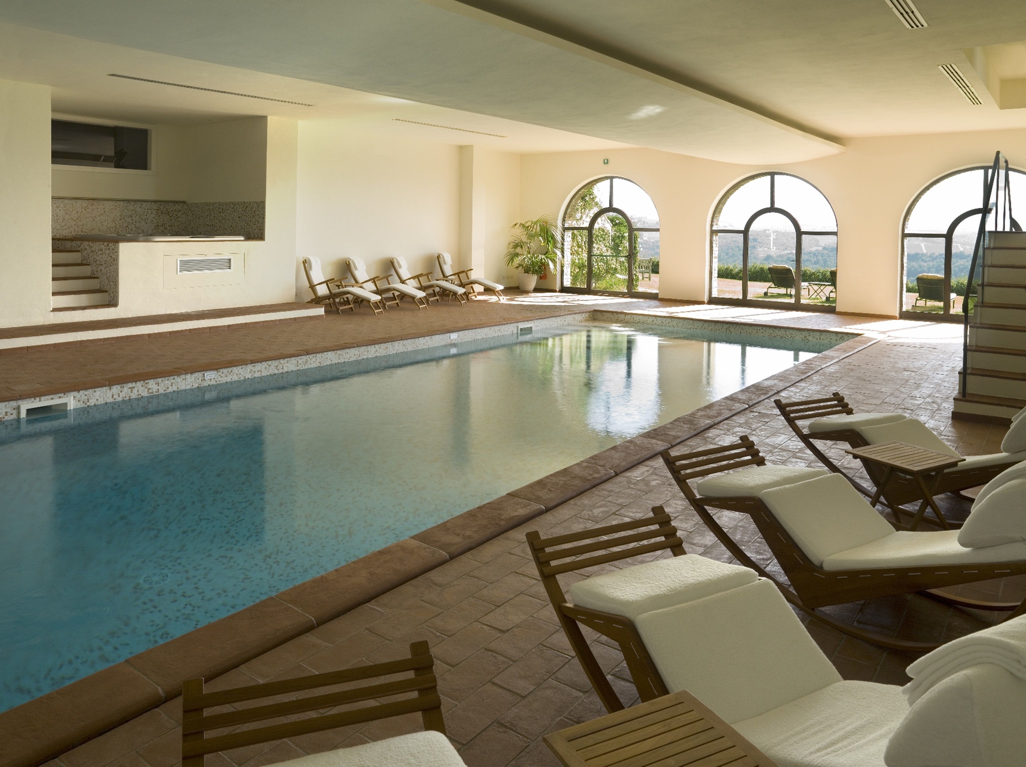 Una piscina interior con sillas de descanso y vistas al exterior.
