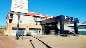 Un hotel con sección de habitaciones ejecutivas y suites, un centro de conferencias y un estacionamiento visible con coches.
