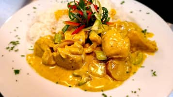 Un plato de comida con arroz y un curry, decorado con cebollines y pimientos rojos.