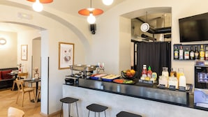 A modern kitchen with a bar area, featuring a coffee machine, a sink, and various food items. - Sir Toby's Midtown - Hostel (Prague)