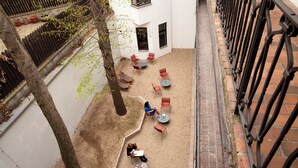 An outdoor patio with multiple tables and chairs, surrounded by a brick wall and a metal fence. - Sir Toby's Midtown - Hostel (Prague)