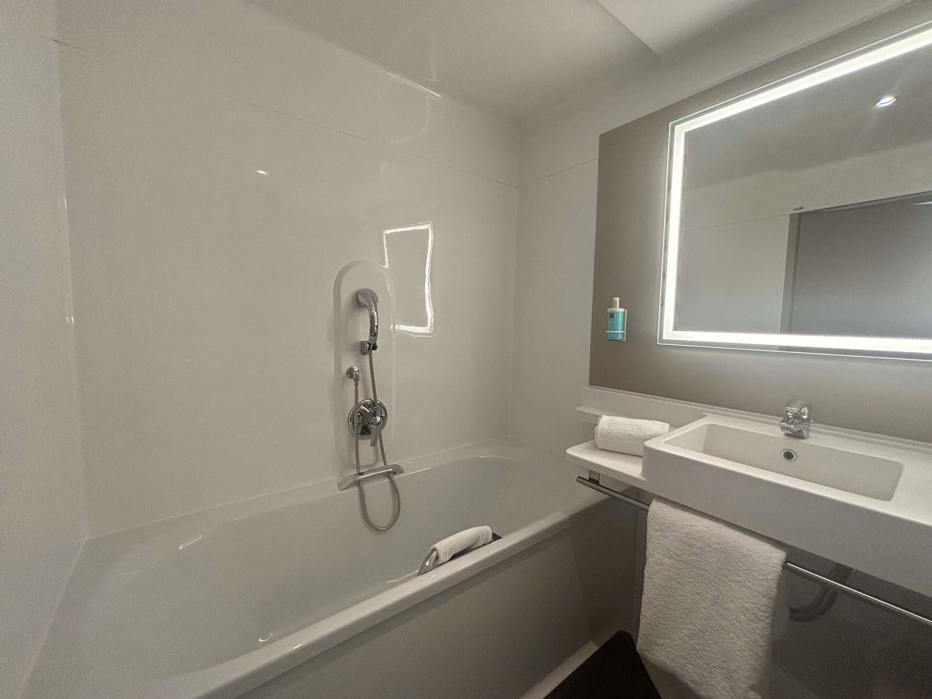 Un baño moderno con bañera, lavamanos y espejo.