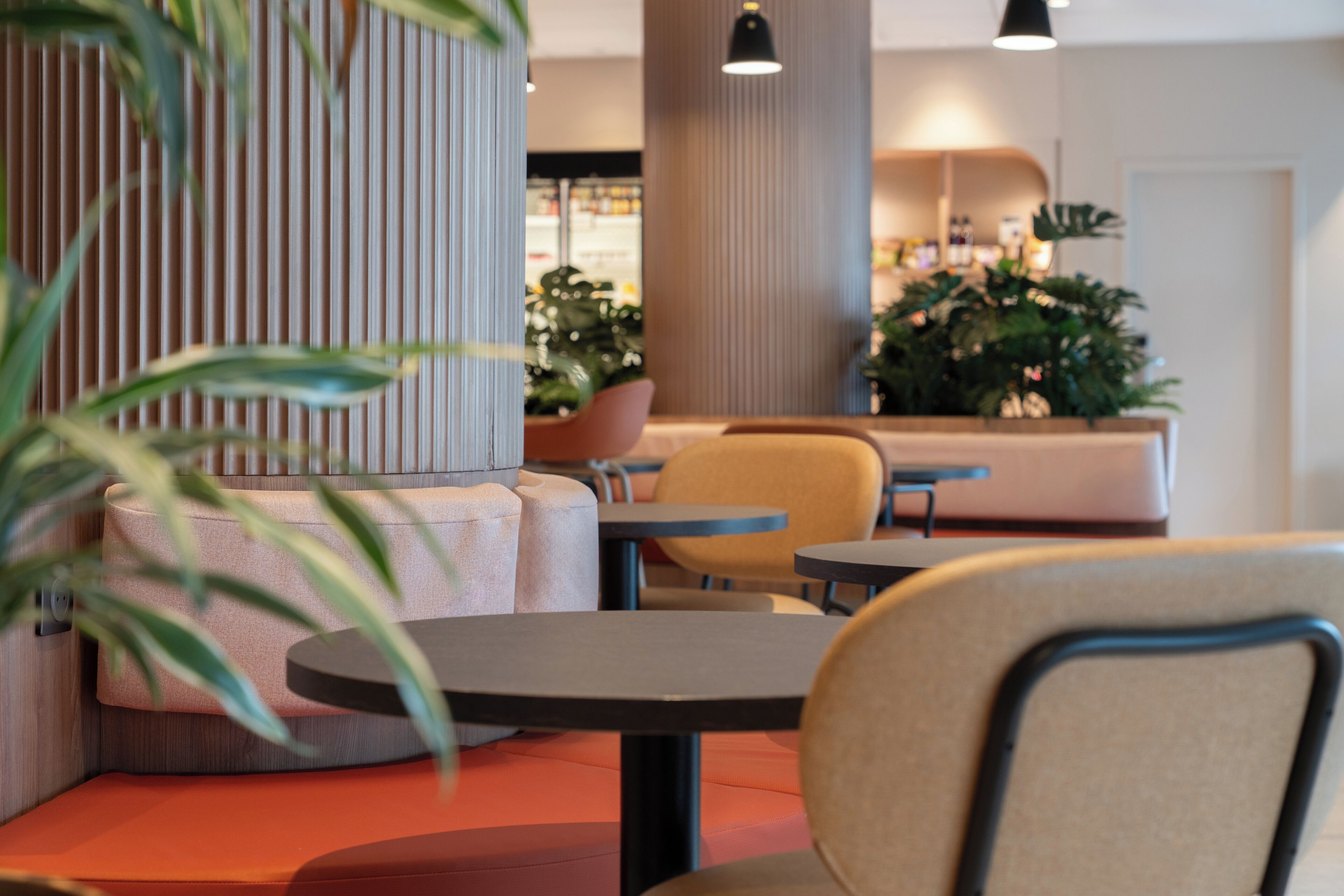 Een modern interieur met zithoeken, tafels en potplanten.