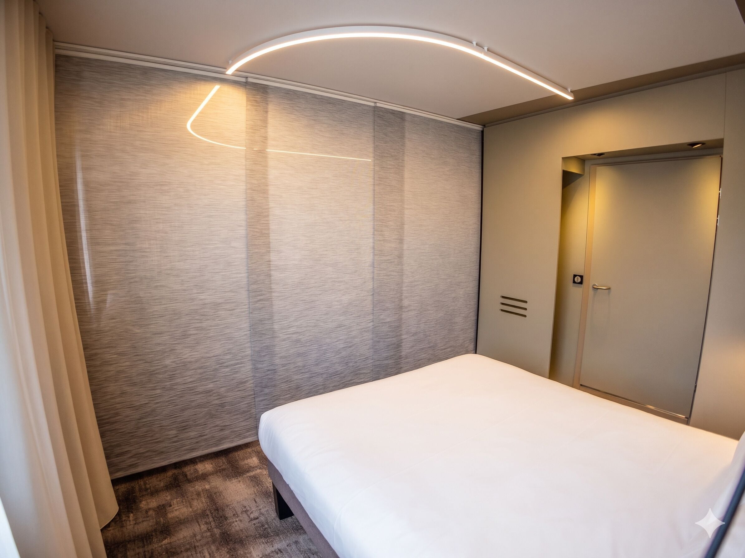 Habitación de hotel con cama, una puerta y pared de textura decorativa.