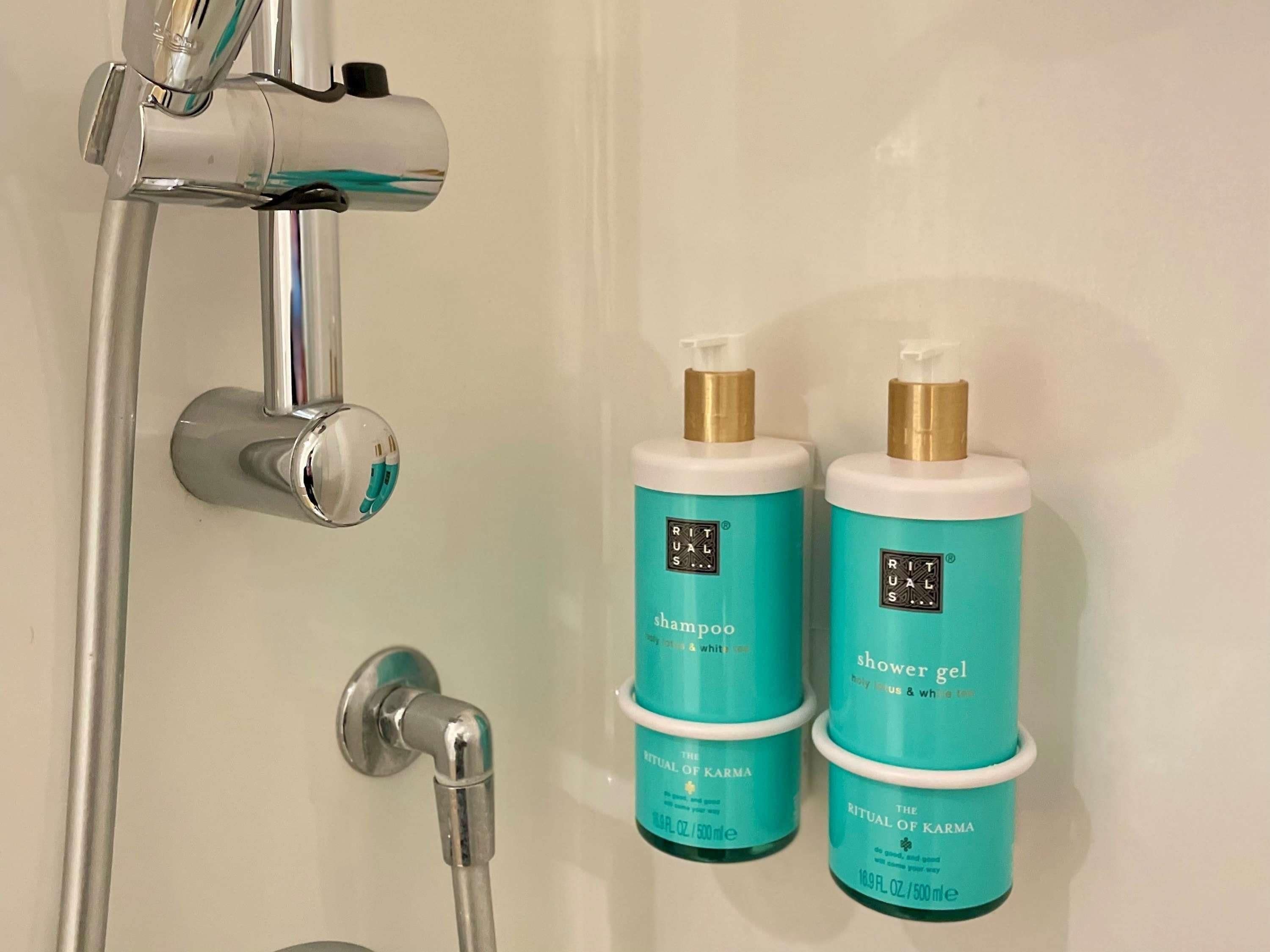 Ein Badezimmer mit Dusche, zwei Flaschen Rituals Shampoo und Duschgel sowie einem Wasserhahn.
