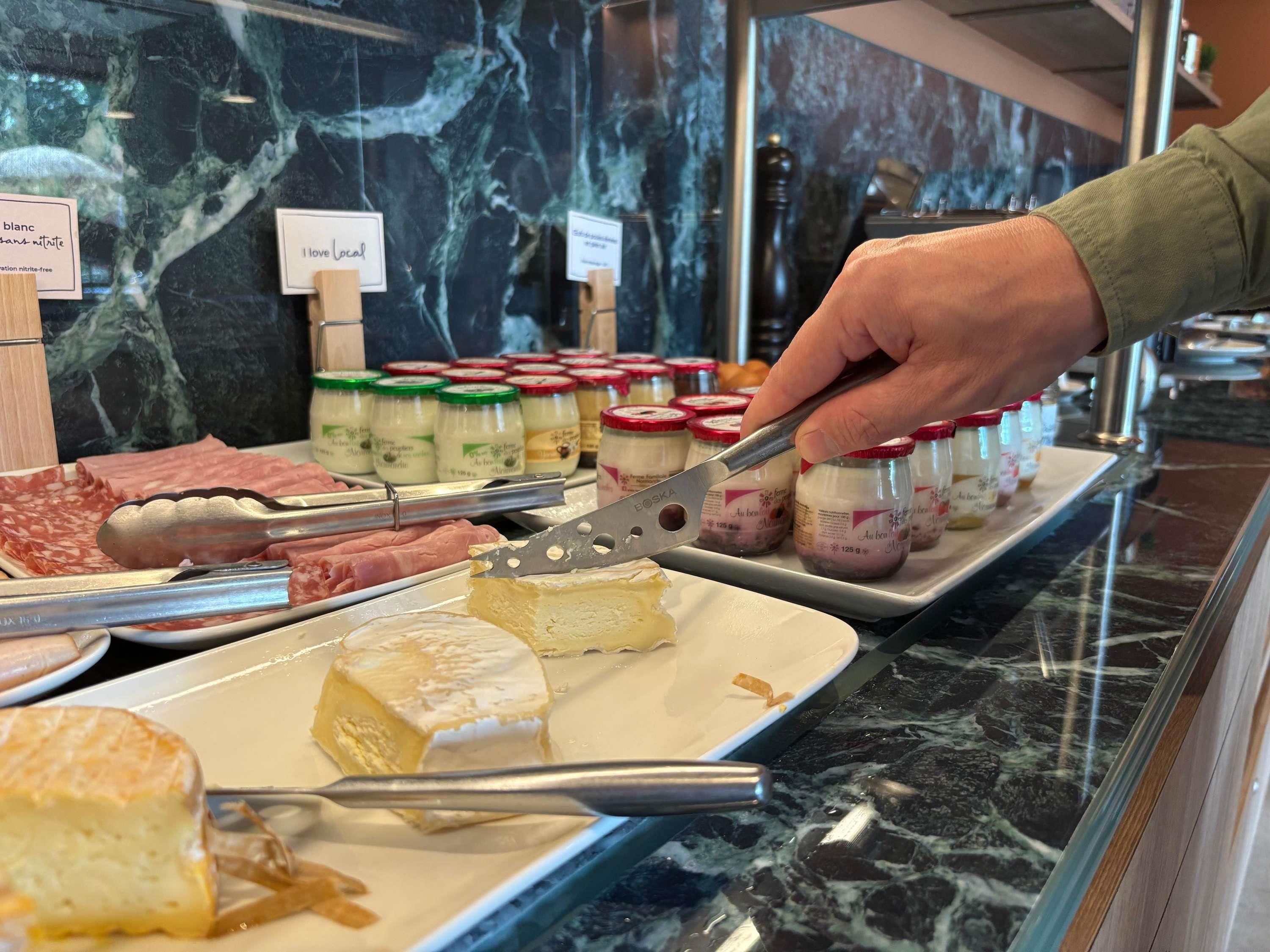 Eine Warenauslage mit Käse und Fleisch, Marmortheke und eine Glasvitrine.