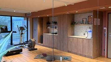 A modern gym with exercise equipment, wooden cabinets, and a large window.
