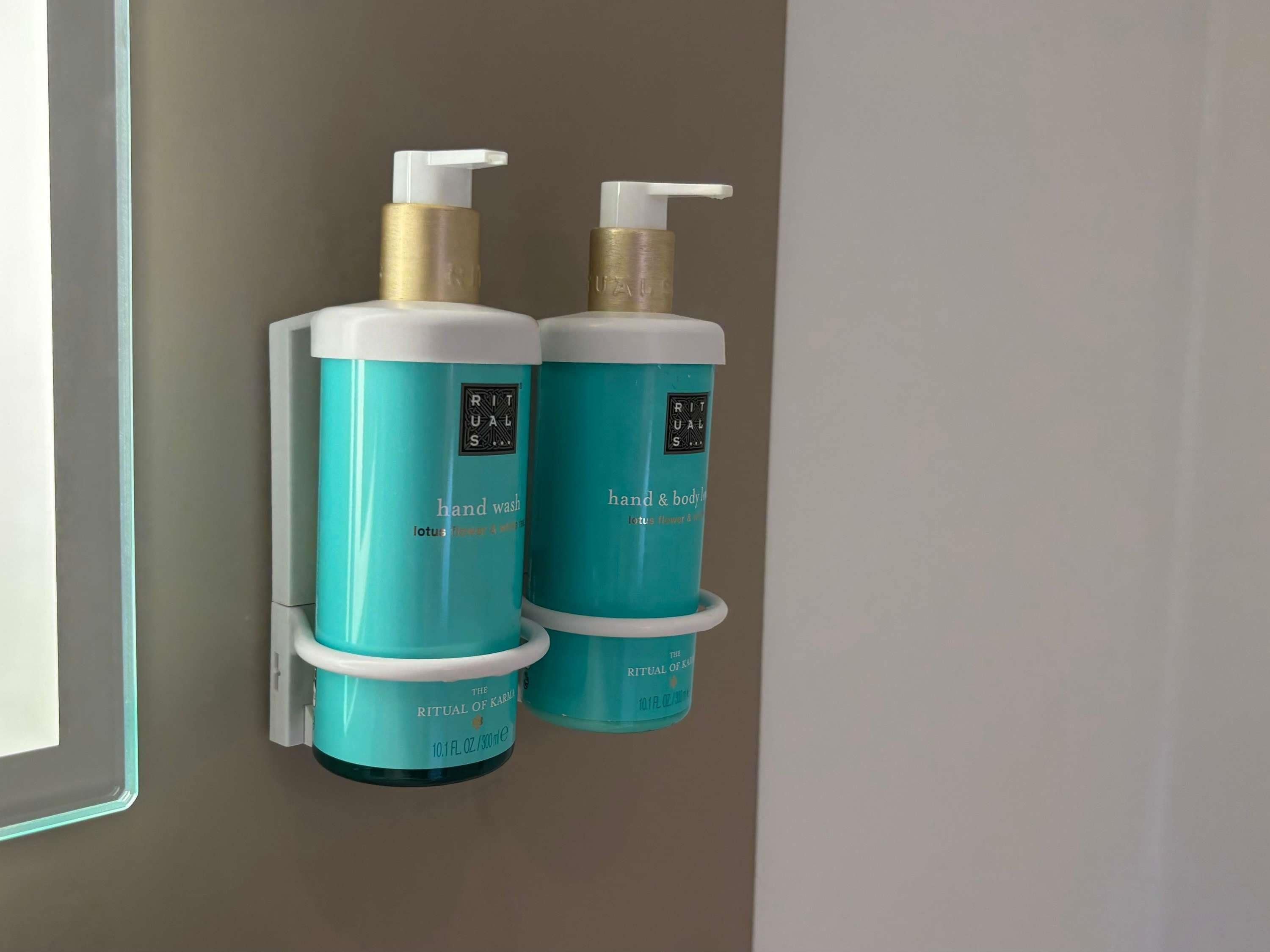 Two teal hand wash bottles with pumps on a wall.