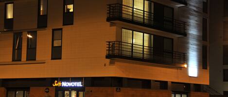 Een modern hotel met een bord waarop 'Suite NOVOTEL' staat en een zichtbare ingang.