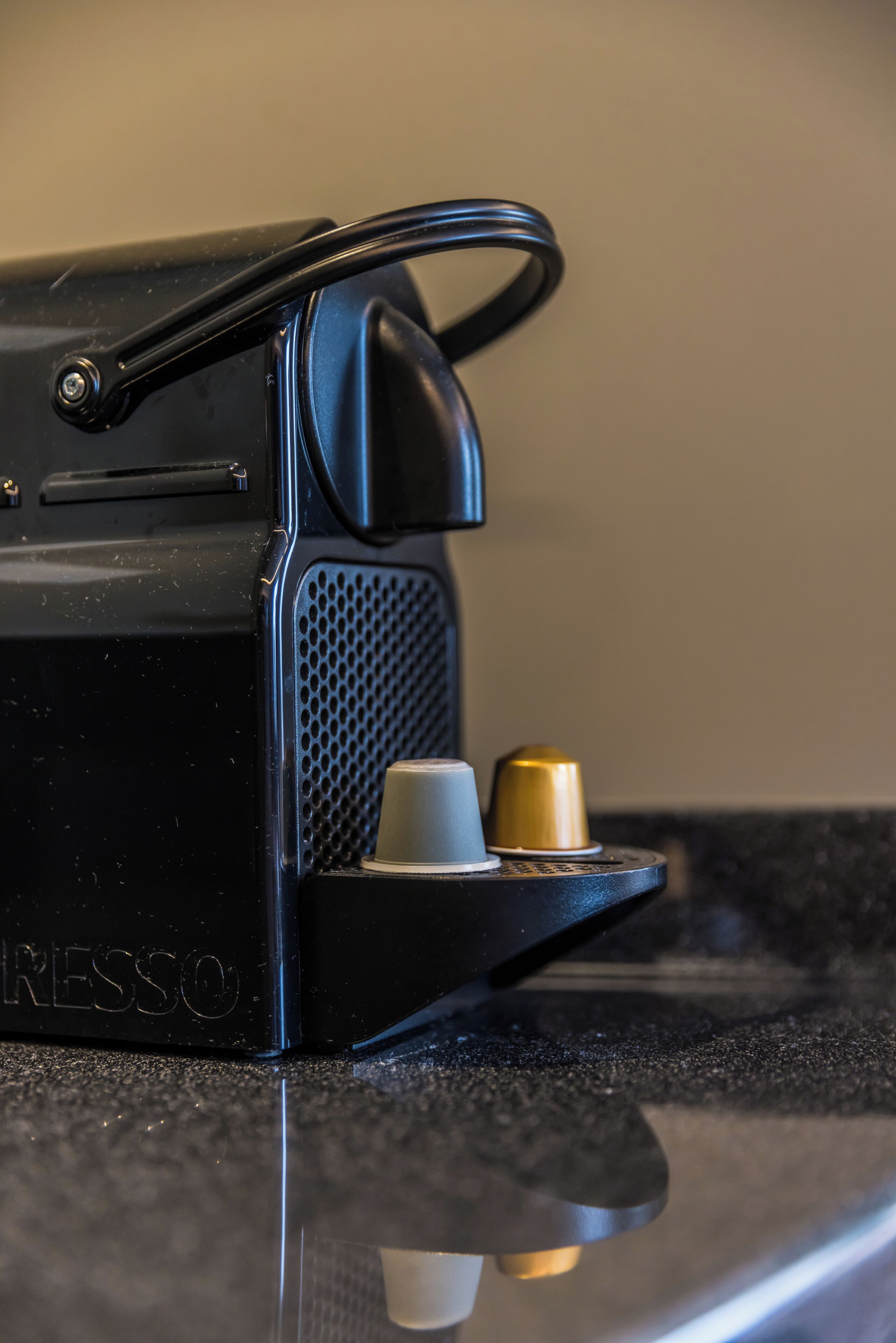 A black coffee machine with a handle, a small cup holder, and a brand name 'RESSO' on the side.